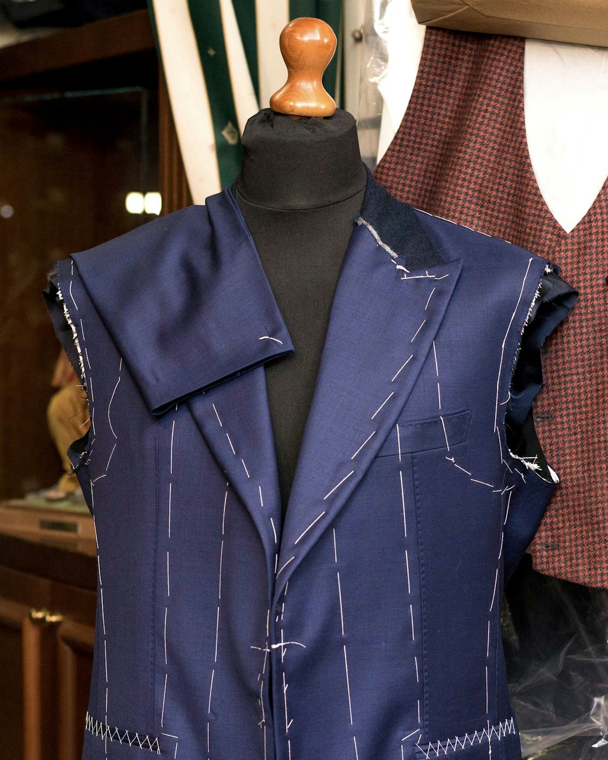 Navy suit jacket in baste on a tailor's form