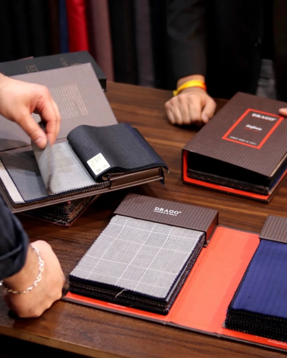 Cloth books open on the table, a hand turning the swatches