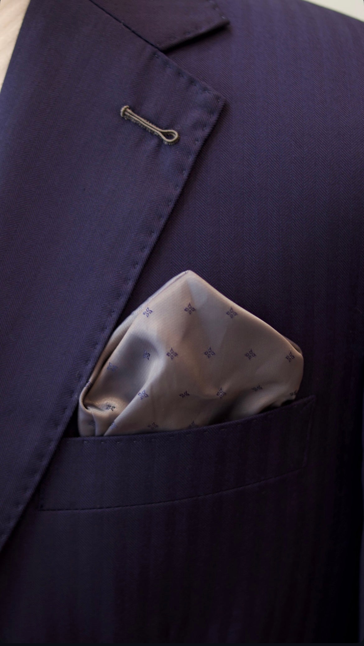 Light patterned pocket square in a soft fold with a navy tailored jacket